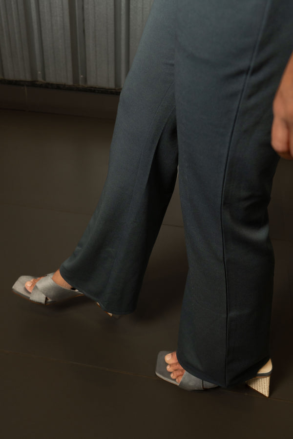 Person wearing smart casual work wear dark grey all day trouser and sandals on a dark floor.