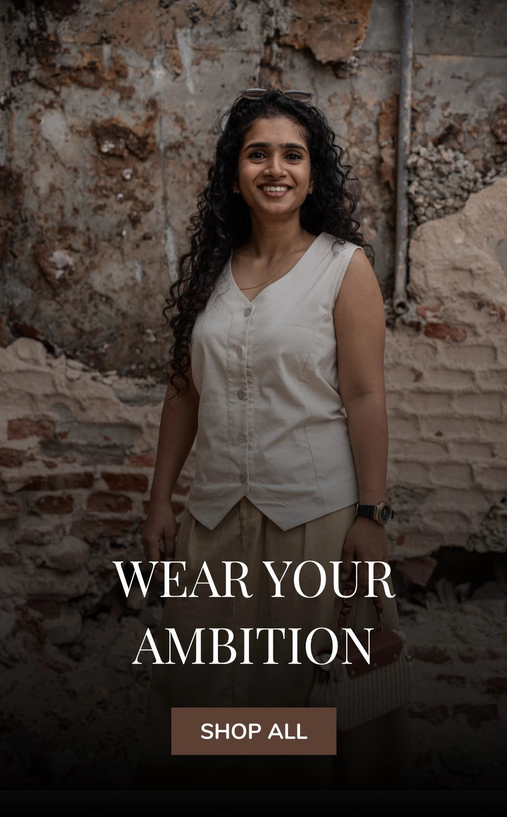 Woman wearing smart casual work wear Latte vest with Filter kaapi skirt standing against a textured wall with 'Wear Your Ambition' text overlay.