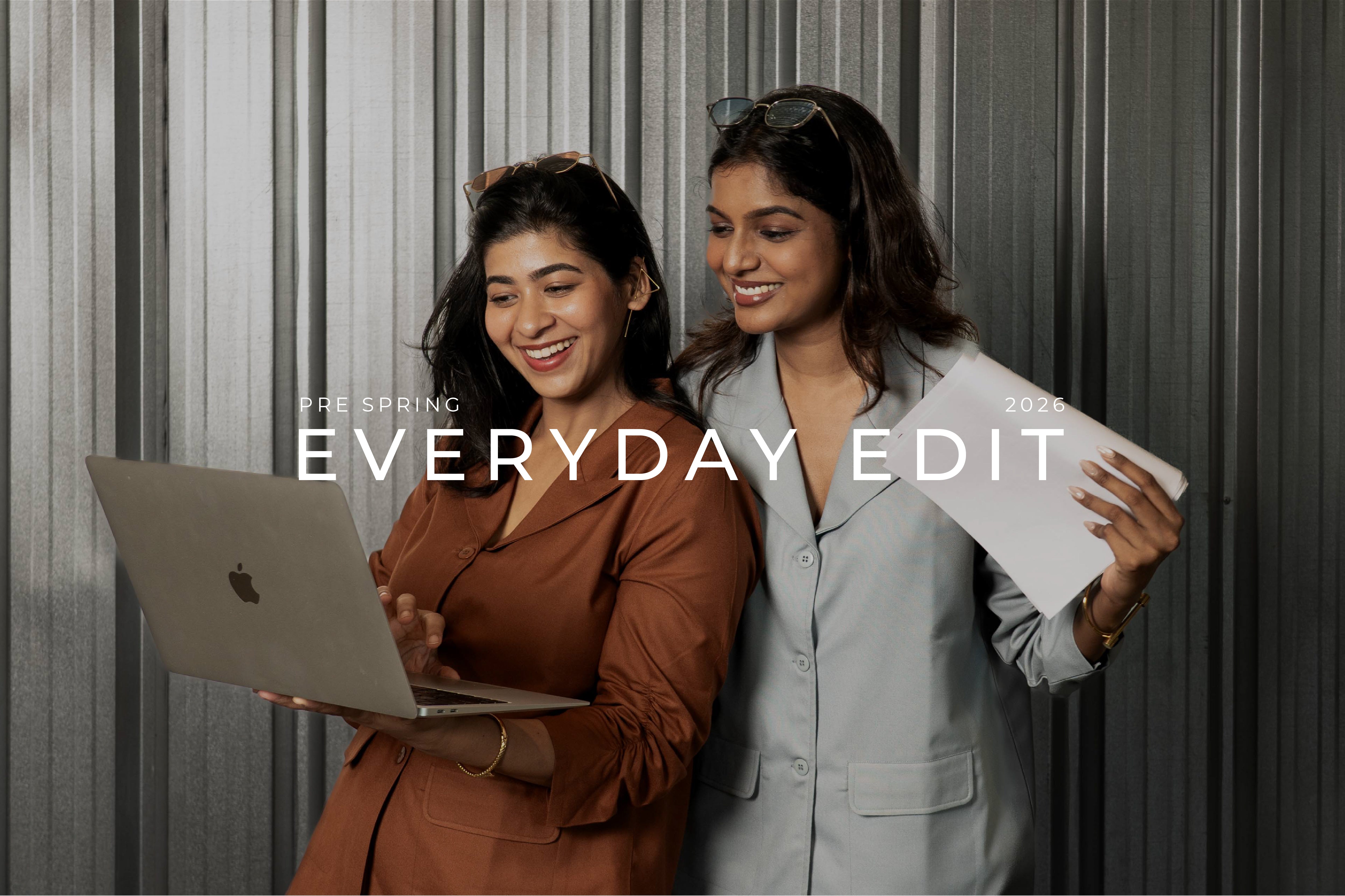 Two women using a laptop in smart casual everyday work wear Shirt Blazers with shades on head and statement earings with 'Pre Spring Everyday Edit 2026' text overlay.