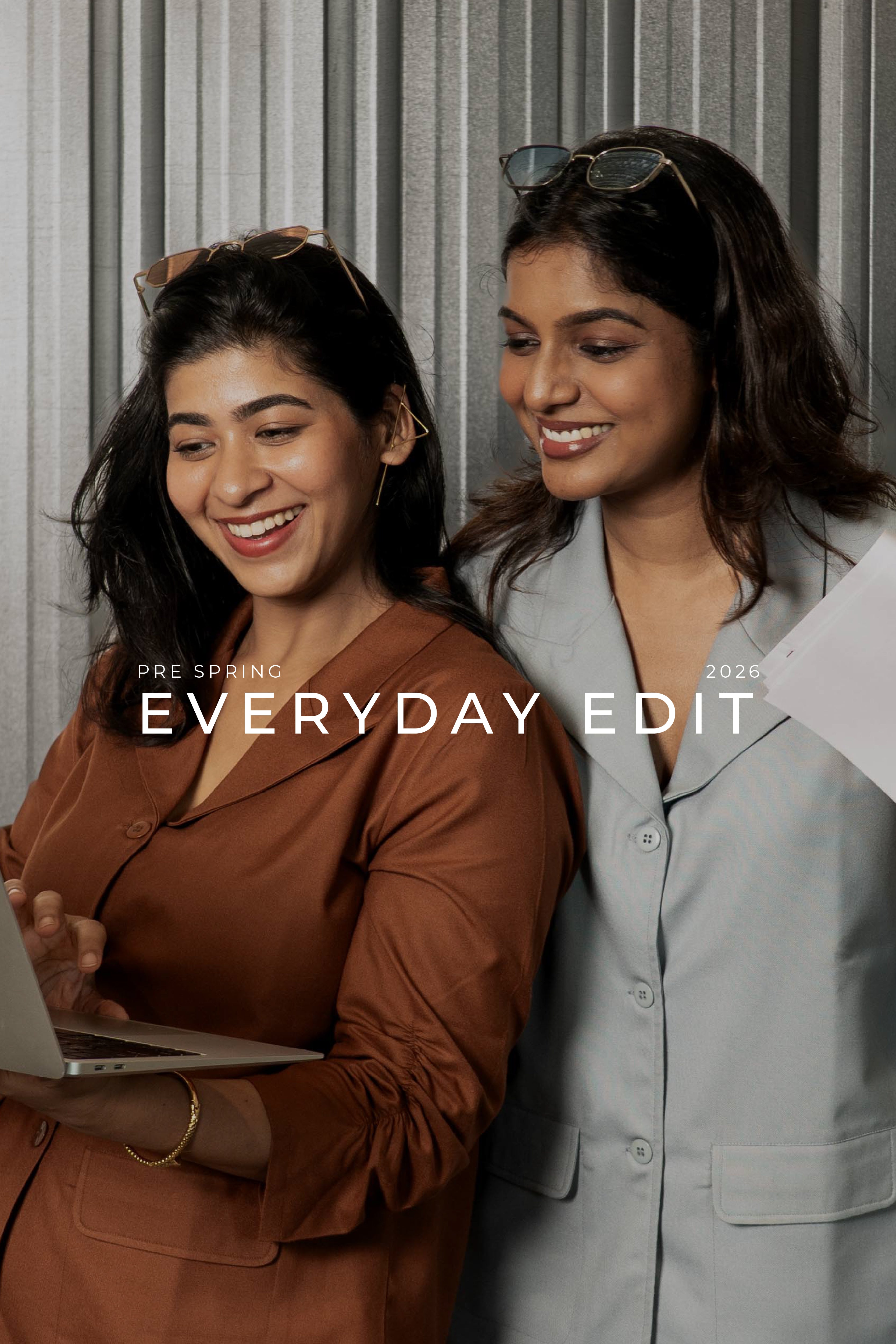Two women using a laptop in smart casual everyday work wear Shirt Blazers with shades on head and statement earings with 'Pre Spring Everyday Edit 2026' text overlay.