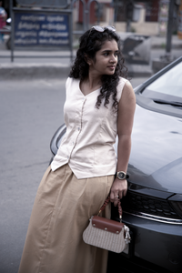 Woman standing next to a car wearing a smart casual work wear beige latte vest and filter kaapi skirt 