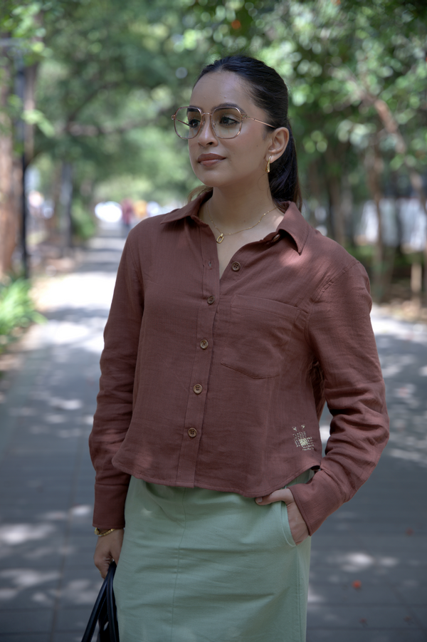 Woman wearing a smart casual work wear mocha brown shirt paired with oprah green skirt outdoors with trees in the background