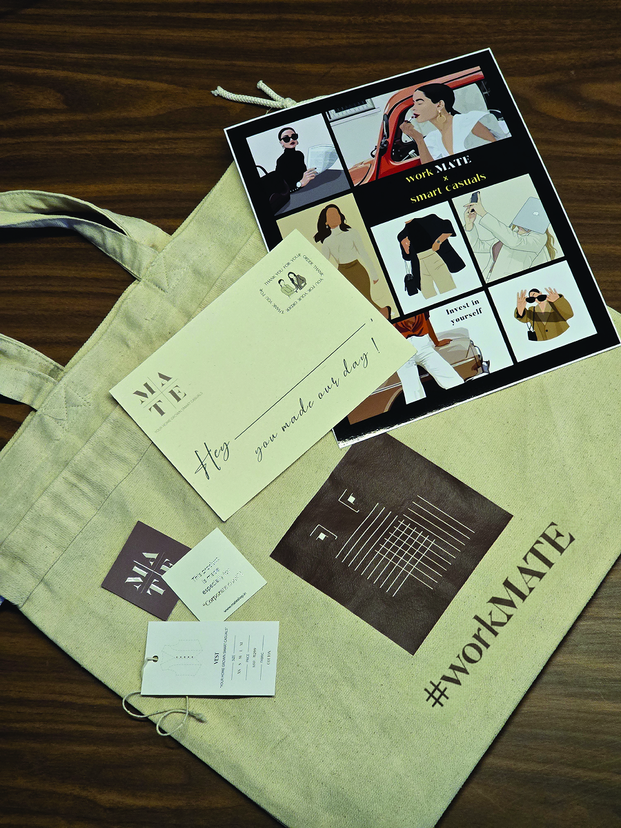 Mate's packaging materials a branded tote bag, thank you card, and tags placed on a wooden surface along with smart casual look book.