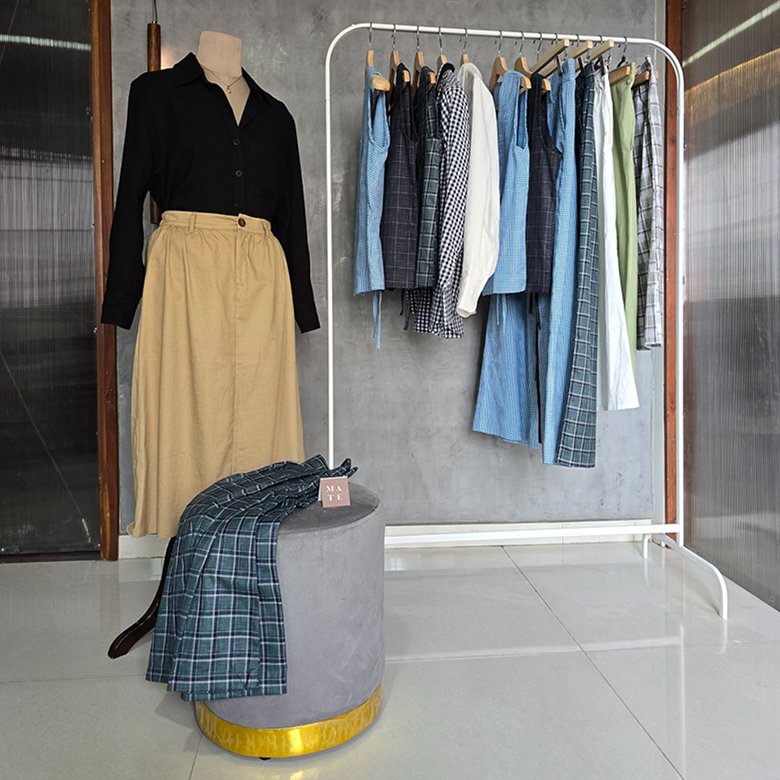 Mannequin wearing a smart casual work wear boardroom basic shirt and filter kaapi skirt with the daily desk collection - vests, shirts, skirts, pants hung on rack.