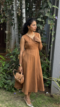 Woman in a smart casual work wear brown suede statement collared toffee dress holding a matching handbag outdoors.